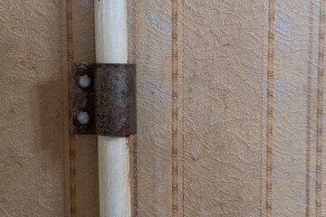 Rusty Clamp on Old Pipe Against Textured Wall