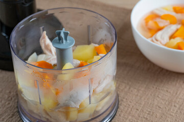 Homemade chicken soup ingredients in blender and bowl