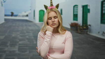 Woman with unicorn diadem standing on city street outdoors looking sleepy and funny in casual clothing featuring blonde hair in urban backdrop