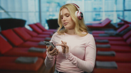 Woman relaxing in a hotel spa with headphones, using a smartphone at a poolside, capturing a serene and modern ambiance.