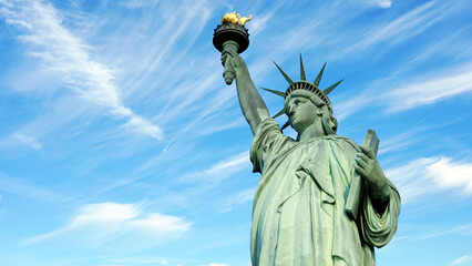 Low angle view of Statue of Liberty against blue sky with white clouds