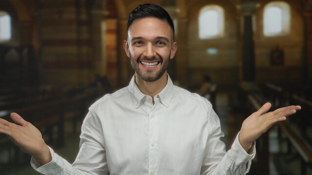 Young man smiling indoors with open arms inside a church setting, symbolizing faith and positivity, illuminated by warm light suggesting a spiritual ambiance.