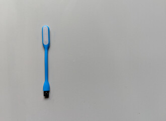 A simple blue USB LED light placed on a light grey background, showing its flexible shape and soft form in a minimal and clean composition.