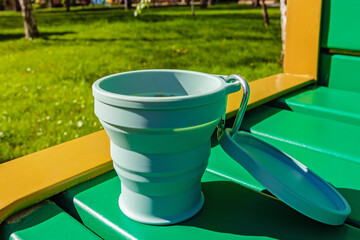 A reusable silicone cup for coffee and tea sits on a park bench. Modern collapsible picnic cup