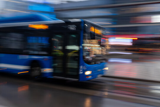 Blauer Stadtbus in schneller Bewegung &ndash; urbaner Nahverkehr im Motion-Blur-Effekt bei Regen
