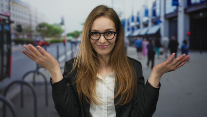 Young caucasian woman with long brown hair and glasses wearing black blazer holds hand to forehead...