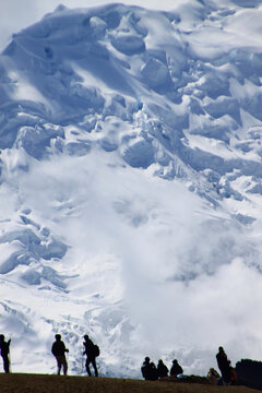 Silhouettes of hikers overlooking a massive snowy mountain glacie