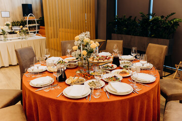 Elegant banquet table with floral centerpiece, candles and appetizers in restaurant