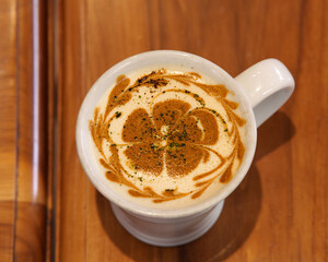 Overhead view of a coffee cup on a wooden table, cozy flat lay with latte foam and natural warm light