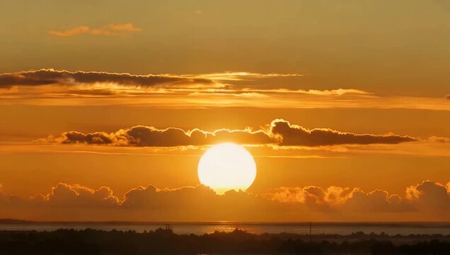This dramatic 4K timelapse captures a fiery red sunrise as clouds drift across the sky recorded with a telephoto lens to emphasize the glowing sun and the peaceful beginning of the day