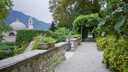 Ornamental garden pathway with defocused balustrade and distant dome in soft bokeh garden; background backdrop copyspace calm.