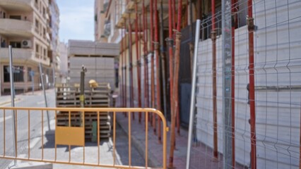 Construction site with scaffolding, pallets and barriers in soft defocused bokeh on a street; background backdrop copyspace backplate.