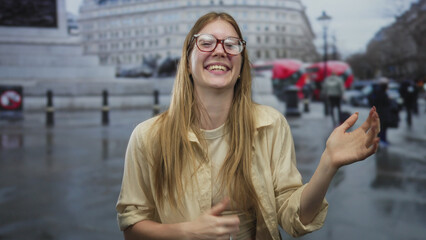 Young woman strums invisible guitar on bustling city street with passing bus behind; lighthearted fun.