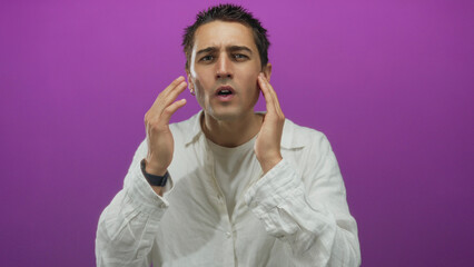 Young man with a white shirt gesturing in front of a vivid purple wall, suggesting communication over an isolated background in a studio setting.