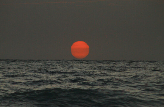 ed sunset over the ocean with dark waves&rdquo;