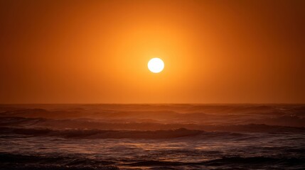 Serene Sunset Over Ocean Waves at Dusk with a Bright Sun Casting Warm Golden Light on the Water Surface