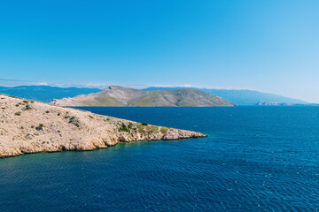 Clear blue sea and rugged island coastline under bright sky