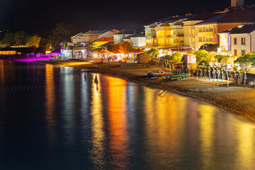 Fototapeta premium Colorful night view of illuminated seaside promenade and beachfront buildings. Baška, Krk island, Croatia