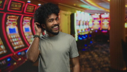 Smiling man in a casino surrounded by vibrant slot machines, embodying a fun indoor gambling experience.