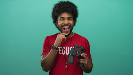 Lifeguard thinking while holding binoculars against green wall, showcasing contemplation and...
