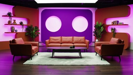A stylish and modern television studio set with comfortable orange leather sofas and vibrant purple ambient lighting