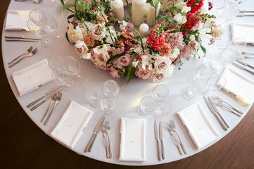 Elegant round wedding table setting with luxury floral centerpiece, crystal glassware, white linens, and candles—perfect for upscale events, receptions, celebrations, and sophisticated dining décor.