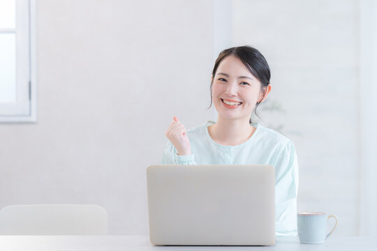 自宅やカフェでパソコンをする笑顔のかわいい女性　　頑張るガッツポーズのカメラ目線