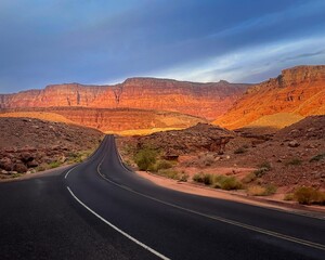 Winding road beneath the looming red walls of Vermillion Cliffs in  Northern Arizona during morning light