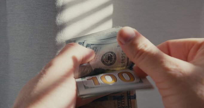 Close-up of man hands counting money 100 dollar bills.