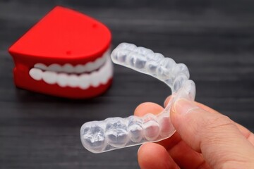 歯の矯正用のマウスピースを持つ人物のクローズアップ