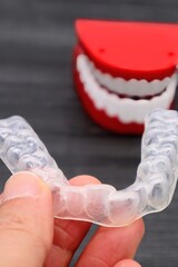 歯の矯正用のマウスピースを持つ人物のクローズアップ