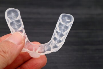 歯の矯正用のマウスピースを持つ人物のクローズアップ