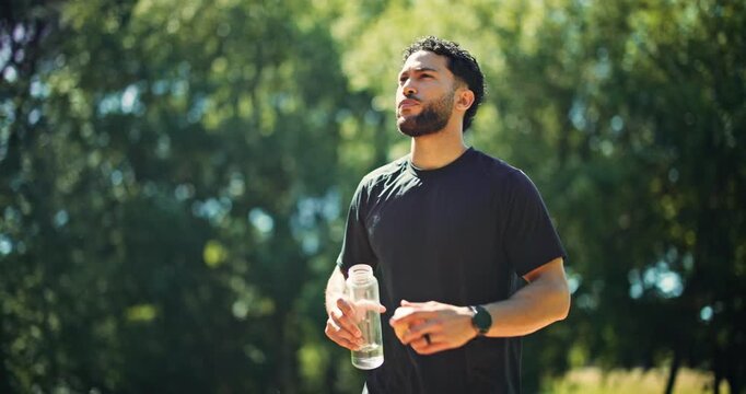 Thirsty, man and drink water in nature with walk for sports hydration, exercise break or thinking. Bokeh, person outdoor and reflection with beverage for electrolytes, training recovery and wellness.