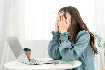 Young Asian businesswoman feeling depressed, thinking, worried while looking at a computer (shock,...