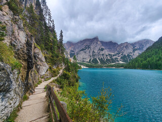 Scenic mountain trail along the turquoise shore of Lago di Braies lake. Dolomites, Italy