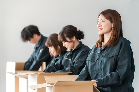 Male and female workers of transportation, logistics, courier, distribution, delivery, warehouse, and delivery companies who pack items into cardboard boxes