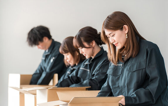 Male and female workers of transportation, logistics, courier, distribution, delivery, warehouse, and delivery companies who pack items into cardboard boxes