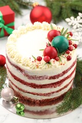 Delicious sponge cake with Christmas decor and red currants on white marble table, closeup