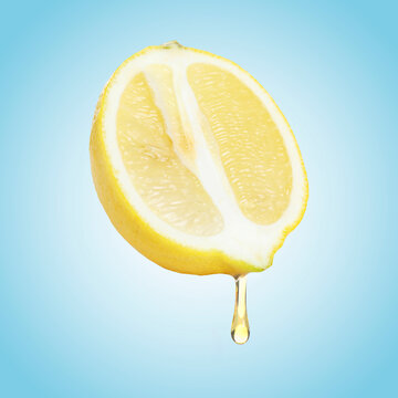 Fresh lemon on light blue background. Drop of juice dripping from citrus fruit
