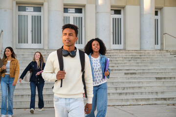 Diverse students walking down steps of a university building, ready for class