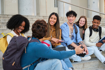 Diverse students sitting, smiling, and discussing on steps outside university building