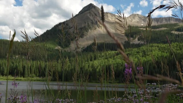 Mountain peak near an alpine lake with clouds passing by near Kebler Pass, Crested Butte, Colorado on a warm summer day with bright blue skies.
