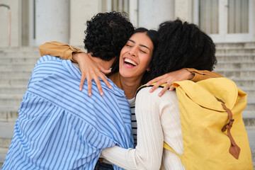Obraz premium Happy students embracing, sharing a group hug, and smiling on university campus steps