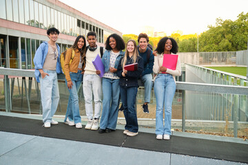 Obraz premium Diverse university students smiling, holding books and folders, connecting on campus
