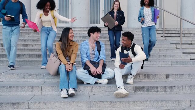 Group of multiethnic university students talking and socializing on the steps outside the college building