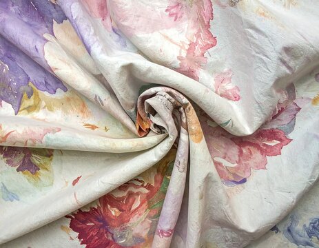 Close-up of draped, watercolor floral fabric in pastel shades, showcasing texture and folds