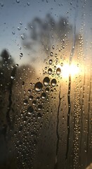 Close-up of a rain-covered window with water droplets during sunset, creating a serene and reflective atmosphere