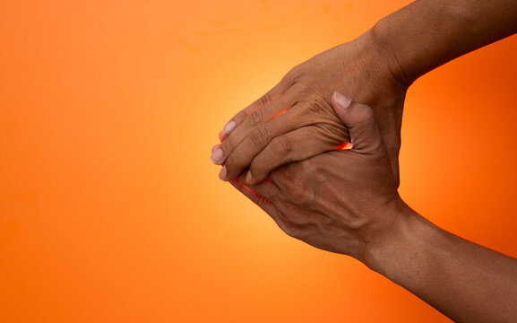 Close-up of human hands performing a gentle self-massage on a bright, contrasting background.