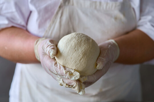 Hands carefully shaping fresh dough in a kitchen during a baking session
