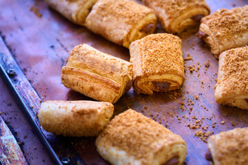Freshly baked filled rolls arranged on a rustic tray with crumb topping in a cozy bakery setting